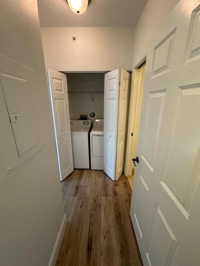 washroom with washing machine and clothes dryer, a textured ceiling, and hardwood / wood-style floors