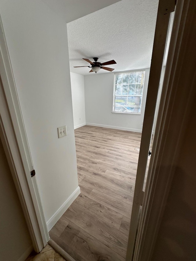 hall featuring light wood-type flooring and a textured ceiling