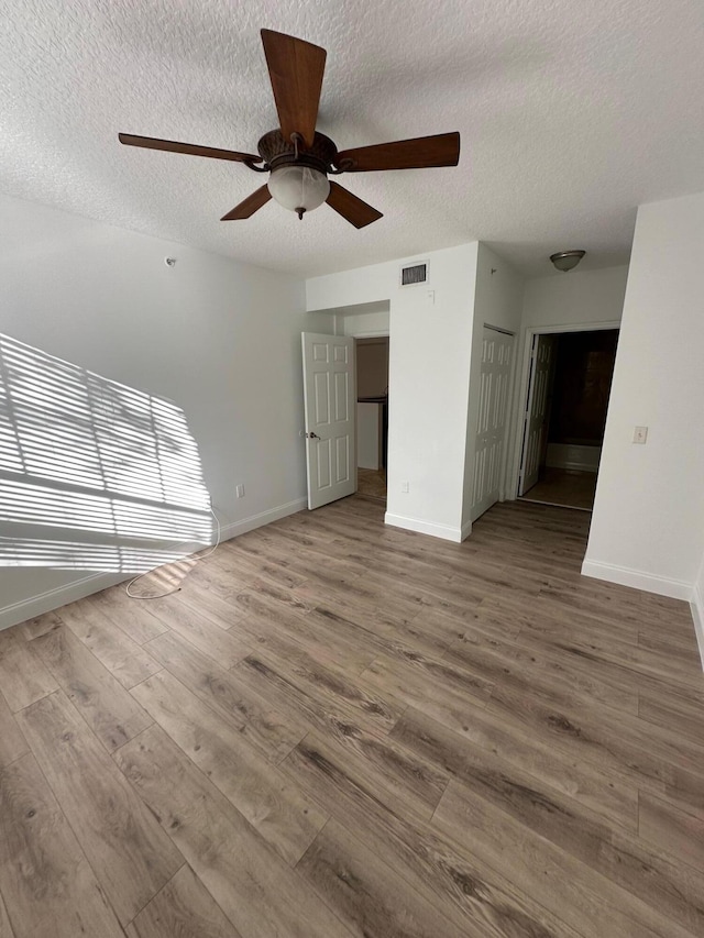 unfurnished living room with a textured ceiling, hardwood / wood-style flooring, and ceiling fan