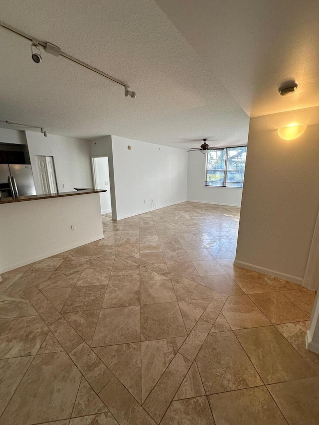 empty room with track lighting, a textured ceiling, and ceiling fan