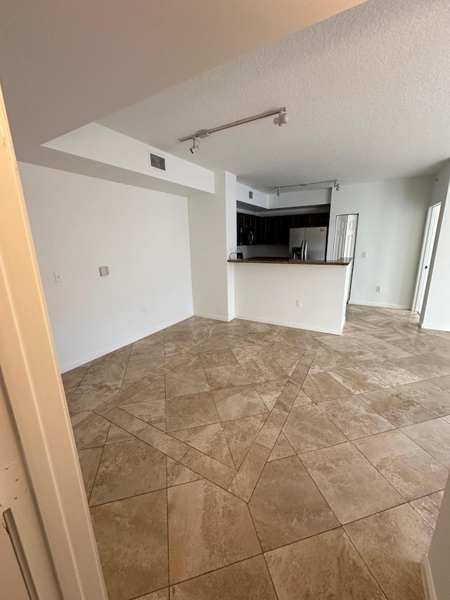 unfurnished living room with a textured ceiling and track lighting