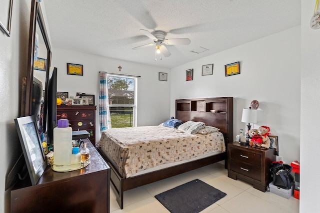 tiled bedroom featuring ceiling fan and a textured ceiling