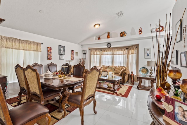 tiled dining space with lofted ceiling and a textured ceiling