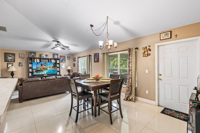 dining area with a textured ceiling, light tile patterned flooring, and ceiling fan with notable chandelier