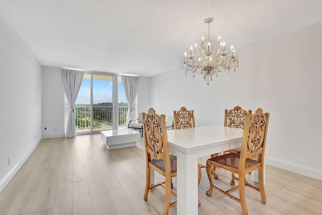 dining space with a chandelier, a wall of windows, light wood finished floors, baseboards, and a textured ceiling