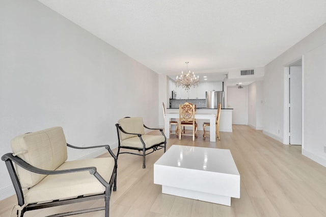 dining area with a notable chandelier, light wood-type flooring, visible vents, and baseboards