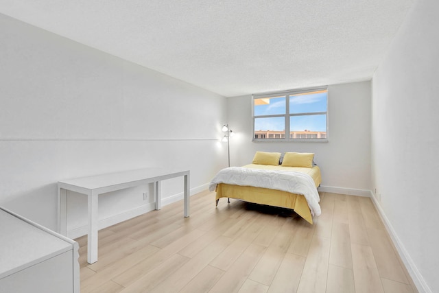 bedroom featuring light hardwood / wood-style floors and a textured ceiling