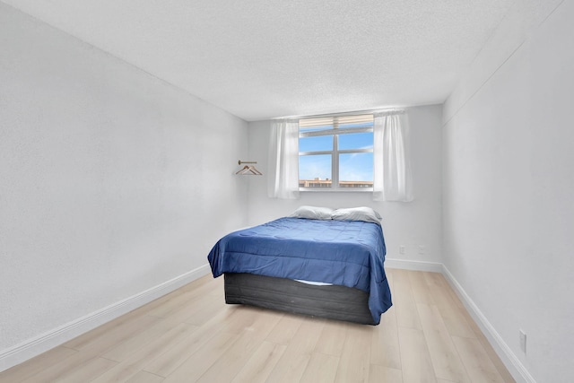 bedroom featuring a textured ceiling, wood finished floors, and baseboards