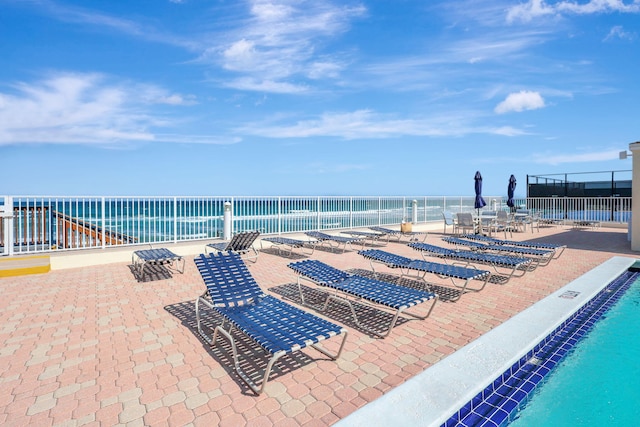 view of pool featuring a view of the beach, a patio area, and a water view