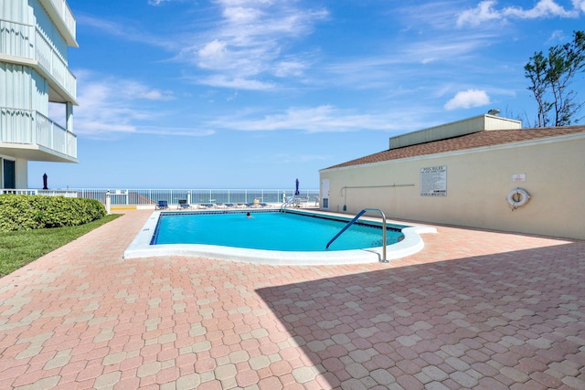 view of swimming pool featuring a patio area and a water view