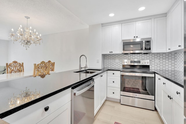 kitchen featuring white cabinets, decorative backsplash, dark countertops, stainless steel appliances, and a sink