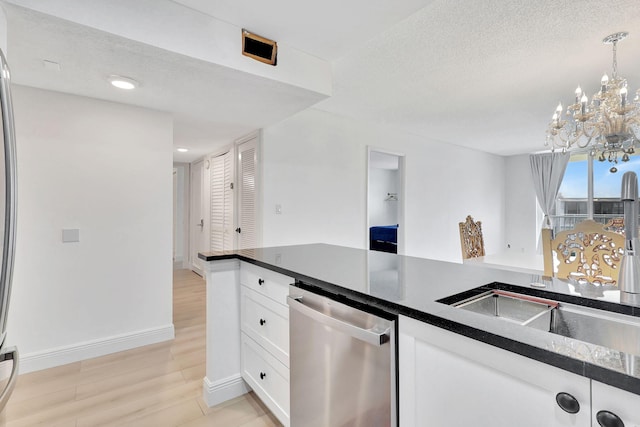 kitchen with a chandelier, dark countertops, dishwasher, a sink, and white cabinetry