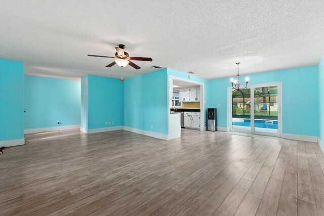 unfurnished living room featuring light wood-type flooring, a textured ceiling, and ceiling fan with notable chandelier