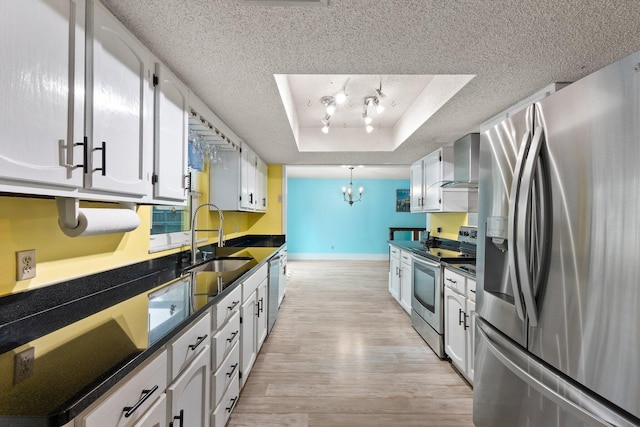 kitchen featuring white cabinetry, appliances with stainless steel finishes, a raised ceiling, sink, and light hardwood / wood-style flooring