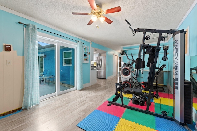 exercise area with ceiling fan, wood-type flooring, and a textured ceiling