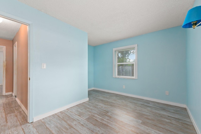 spare room with light wood-type flooring and a textured ceiling