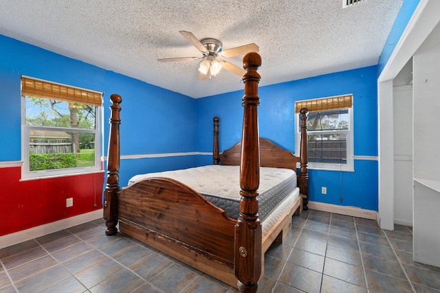 tiled bedroom featuring multiple windows, a textured ceiling, and ceiling fan