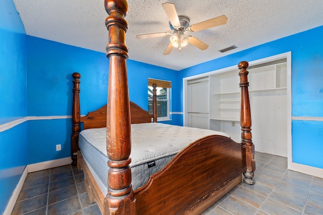 bedroom with ceiling fan, a textured ceiling, a closet, and dark tile patterned flooring