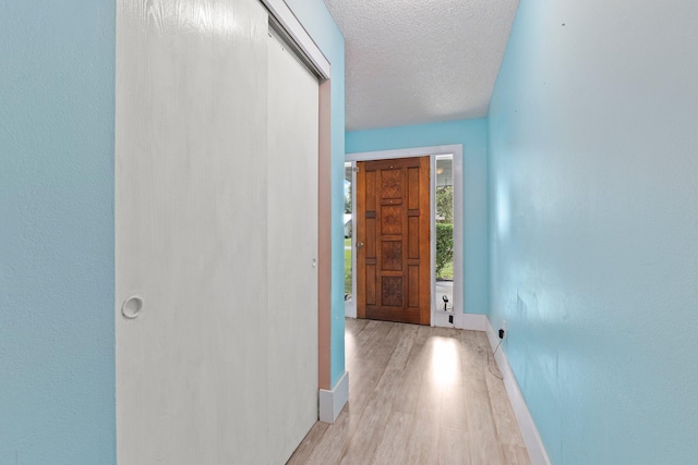 corridor featuring light hardwood / wood-style floors and a textured ceiling