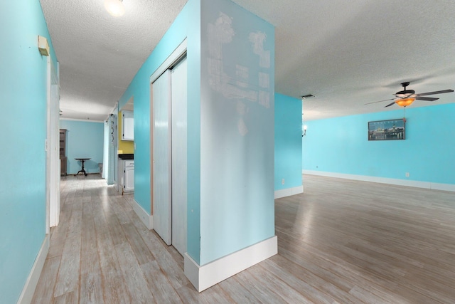 corridor featuring light hardwood / wood-style flooring and a textured ceiling