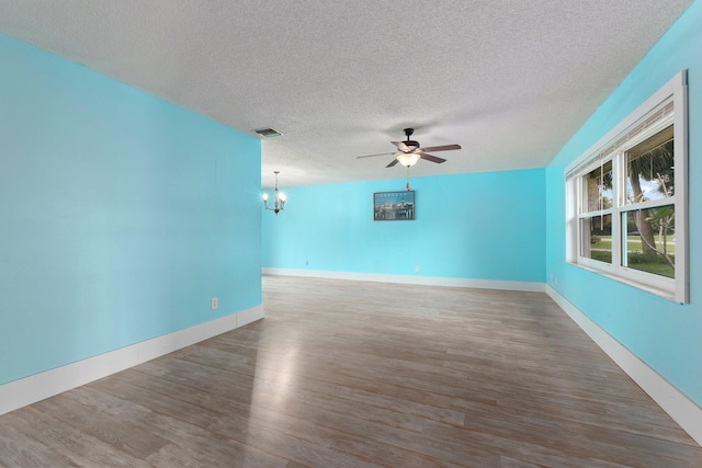 unfurnished room with a textured ceiling, hardwood / wood-style flooring, and ceiling fan with notable chandelier