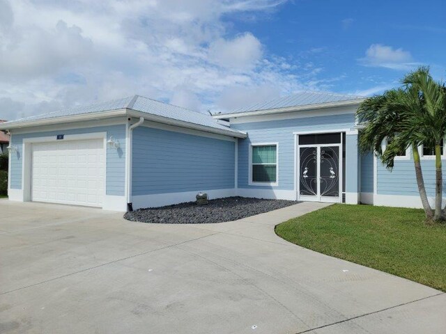 single story home with a front yard, an attached garage, and concrete driveway