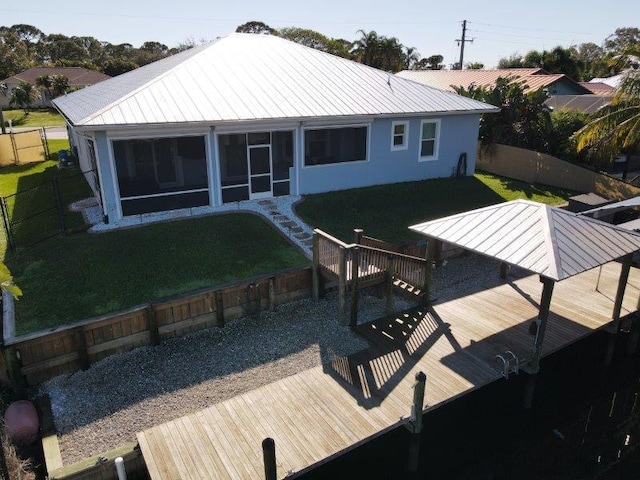 rear view of property featuring a lawn, metal roof, a deck, and a sunroom