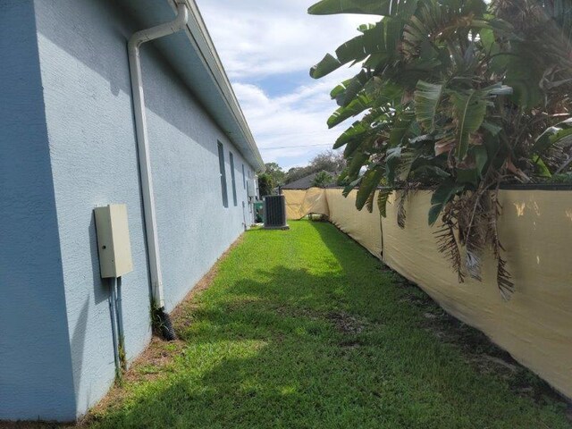 view of yard with central AC unit and fence