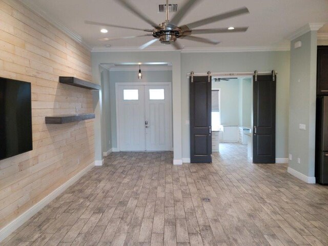 entrance foyer featuring visible vents, a barn door, wood finished floors, and ornamental molding