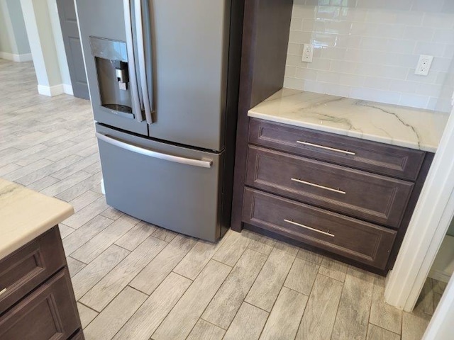 kitchen featuring decorative backsplash, wood tiled floor, dark brown cabinetry, and stainless steel fridge with ice dispenser