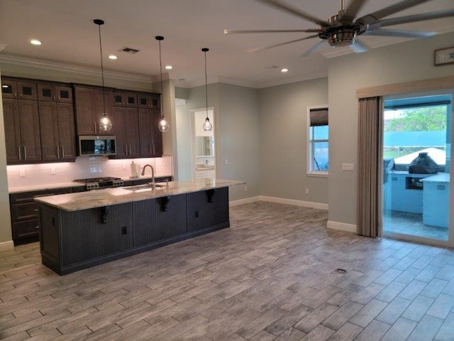 kitchen featuring visible vents, a sink, stainless steel microwave, light wood-type flooring, and backsplash