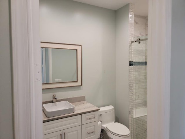 bathroom featuring toilet, vanity, and a tile shower