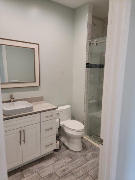 full bathroom featuring vanity, toilet, a stall shower, and wood tiled floor