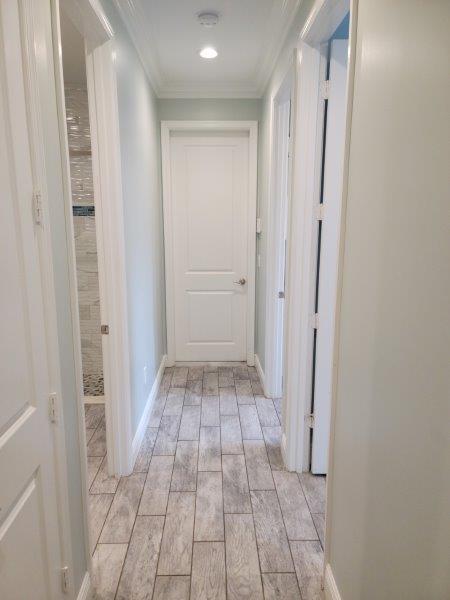 corridor with baseboards, wood finish floors, and ornamental molding