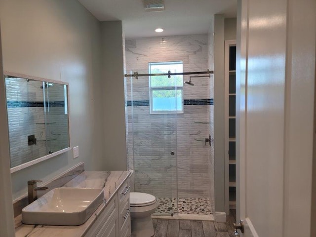 bathroom featuring vanity, a shower stall, toilet, and wood finished floors