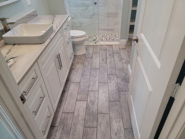 bathroom with vanity, toilet, a stall shower, and wood tiled floor