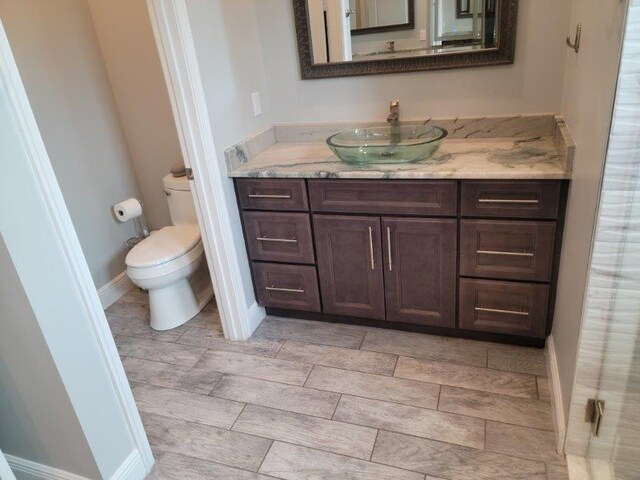 bathroom featuring vanity, toilet, and baseboards