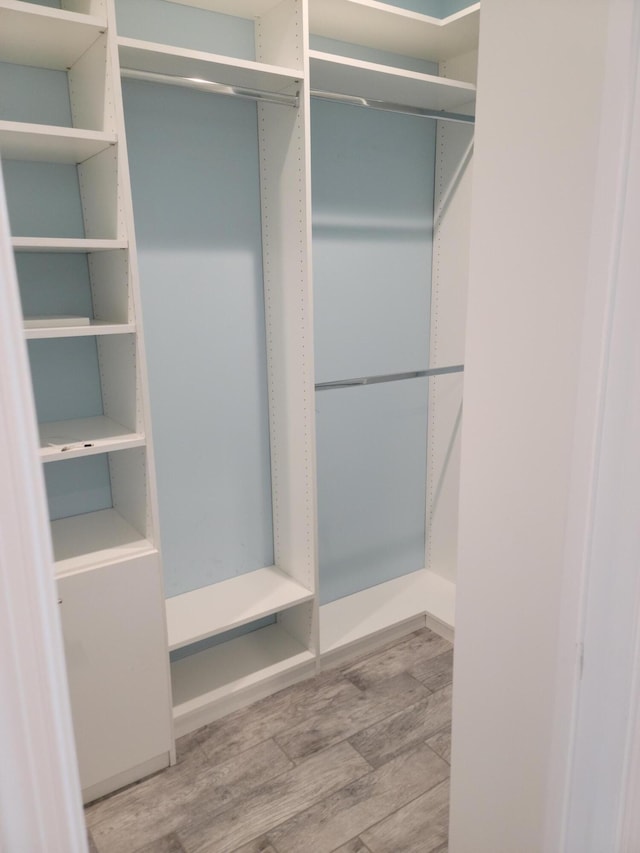 walk in closet with wood finished floors