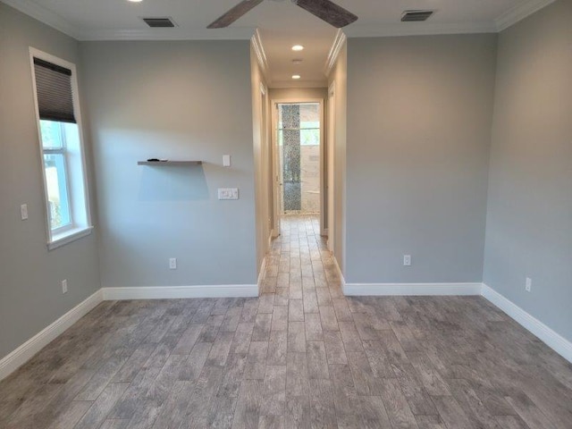 unfurnished room featuring visible vents, baseboards, wood finished floors, and crown molding