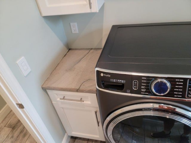 clothes washing area featuring laundry area, washer / clothes dryer, wood finished floors, and baseboards