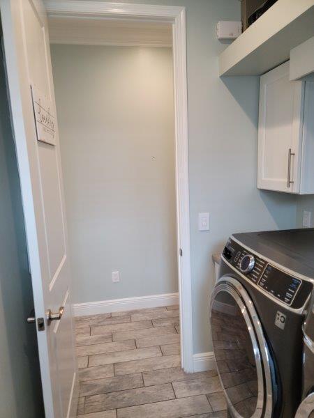 laundry room with wood finish floors, baseboards, and cabinet space