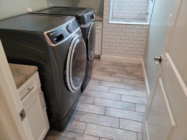 washroom featuring laundry area, washing machine and dryer, baseboards, and wood finish floors