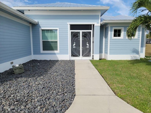 view of exterior entry featuring metal roof and a yard