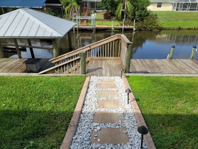 view of dock with a lawn and a water view