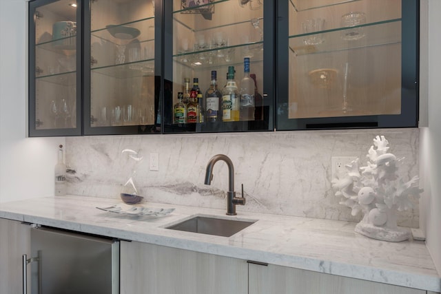 bar featuring sink, light brown cabinets, light stone counters, refrigerator, and decorative backsplash