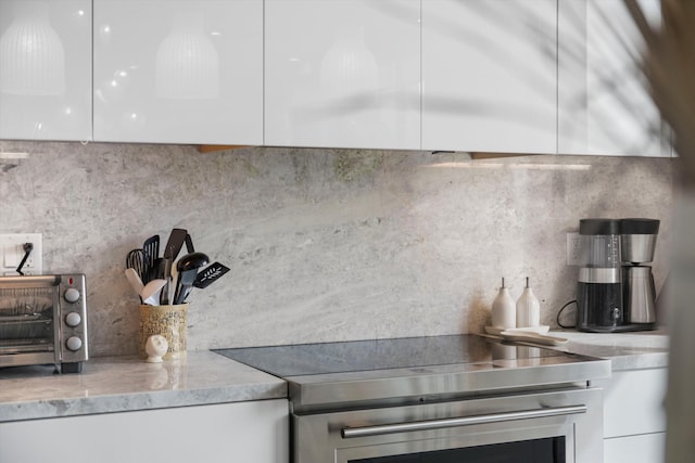 kitchen featuring white cabinets, light stone countertops, and tasteful backsplash