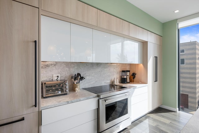 kitchen featuring white cabinets, electric range, light hardwood / wood-style floors, and backsplash