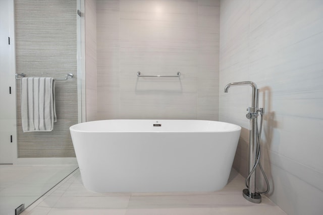 bathroom with tile patterned floors, a bathing tub, and tile walls