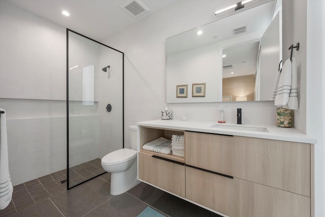 bathroom with tile patterned flooring, a tile shower, vanity, and toilet