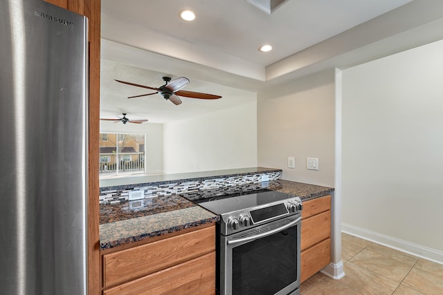 kitchen with appliances with stainless steel finishes, backsplash, ceiling fan, light tile patterned floors, and dark stone countertops